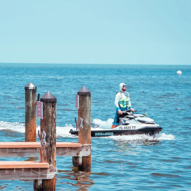 A rider on a jet ski passing the wooden dock pilings at the Snappers marina.